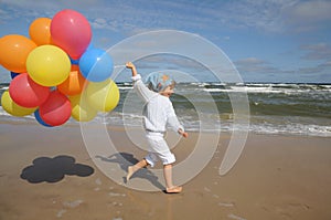 Little girl with balloons on the beach