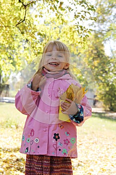 Little girl with basket and leaves in autumn park