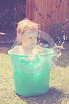 Little girl bathes in a bucket