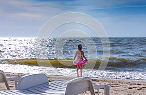 Little girl in a bathing suit, stands on the seashore