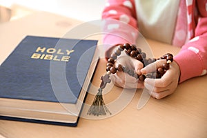 Little girl with beads praying at table