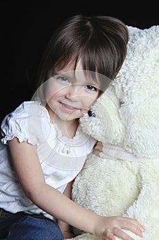 Little girl with bear on a black background photo