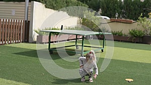 A little girl beats a ball with a tennis racket.