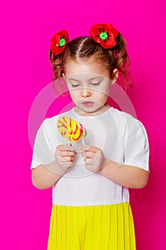 Little girl in a beautiful dress with a big candy lollipop