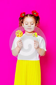 Little girl in a beautiful dress with a big candy lollipop