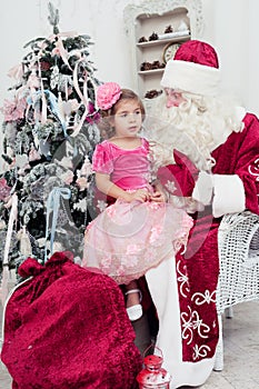 Little girl in a beautiful pink dress sits on a lap at Saint Nicolas