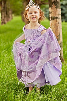 Little girl in beautiful violet gown and crown on