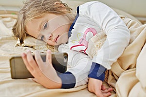Little girl in bed with smartphone