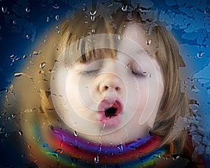 Little girl behind a dewy window