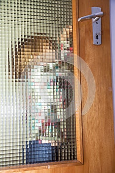 Little girl behind structured glas door