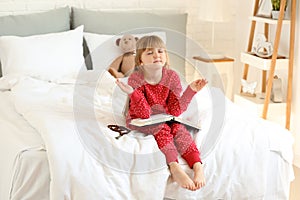 Little girl with Bible praying in bedroom