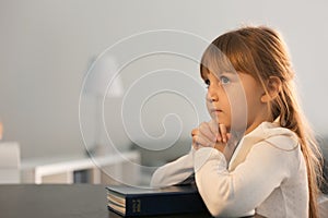 Little girl with Bible praying at home