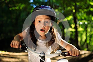 Little girl with bicycle in summer park outdoors