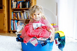 Little girl with a big basket of fresh clean laundry ready for ironing. Happy beautiful toddler and baby daughter