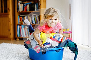 Little girl with a big basket of fresh clean laundry ready for ironing. Happy beautiful toddler and baby daughter