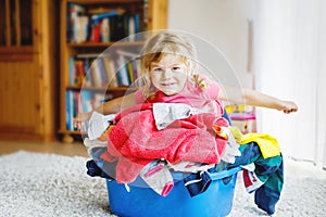 Little girl with a big basket of fresh clean laundry ready for ironing. Happy beautiful toddler and baby daughter