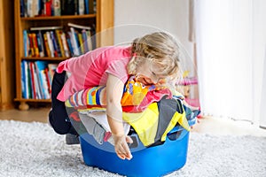 Little girl with a big basket of fresh clean laundry ready for ironing. Happy beautiful toddler and baby daughter