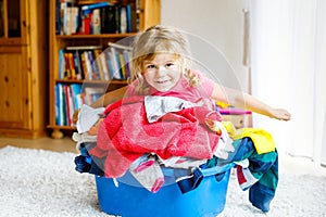 Little girl with a big basket of fresh clean laundry ready for ironing. Happy beautiful toddler and baby daughter