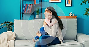 Little girl with big beautiful eyes, stands on couch next to mom, she is happy,