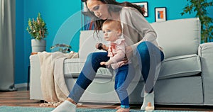 Little girl with big beautiful eyes, sweet baby is standing on sofa next to mom,