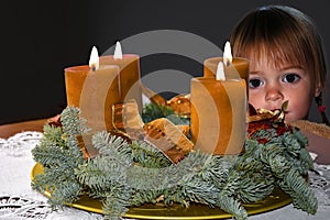 Waiting for christmas, little girl behind a table with advend wreath