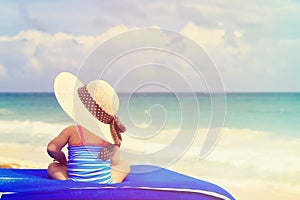 Little girl in big hat on summer beach