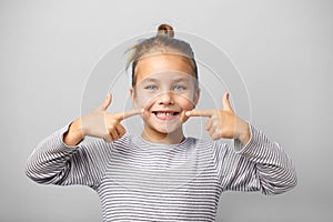 Little girl with big smile shows her white milk teeth.