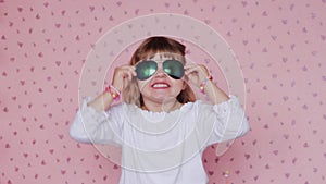 Little girl with big sunglasses, making faces and having fun; children and positive emotions