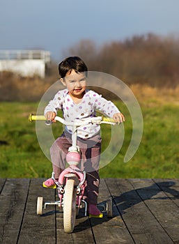 Little girl on a bike near the house