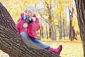 Little girl with binocular sits on inclined tree