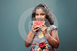 A little girl bites  a slice of watermelon