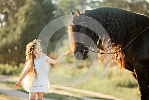 Little girl with black friesian stallion