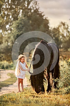 Little girl with black friesian stallion