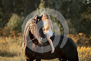 Little girl with black friesian stallion