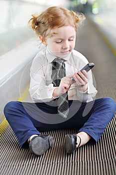 Little girl with black mobile phone sits on