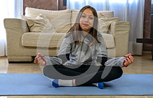 Little girl with black sportswear practicing yoga in the living room at home