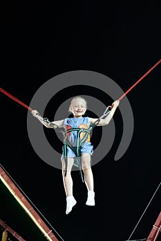 Little girl with blond hair in the air on the catapult ride against the black sky. Fun summer vacation