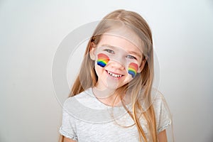 Little girl painted cheeks a rainbow. stay home. photo