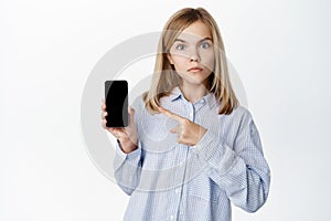 Little girl, blond teen child showing empty phone screen, mobile phone interface, video game on application, standing