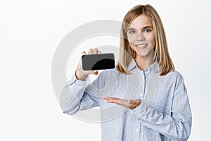Little girl, blond teen child showing empty phone screen, mobile phone interface, video game on application, standing