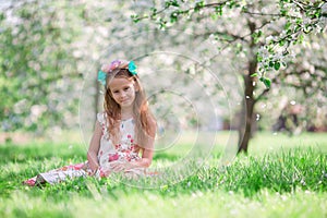 Little girl in blooming cherry tree garden outdoors