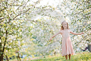 Little girl in blooming cherry tree garden outdoors on Easter eve