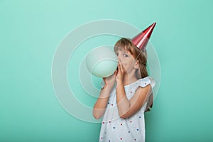 Little girl blowing a balloon and celebrating birthday