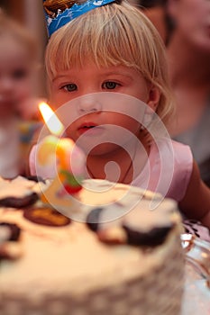 Little girl blowing on birthday cake