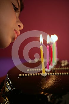 Little girl blowing birthday cake candles