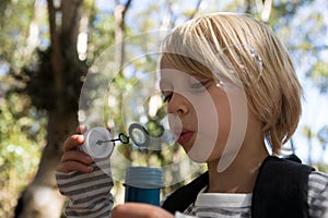 Little girl blowing bubbles on a sunny day in the forest