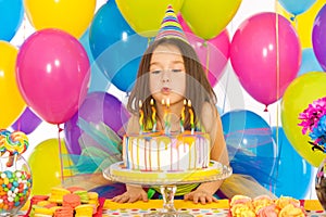 Little girl blowing candles on birthday cake