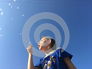 A little girl blowing dandelion seeds.