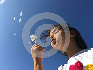 A little girl blowing dandelion seeds.