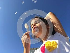 A little girl blowing dandelion seeds.
